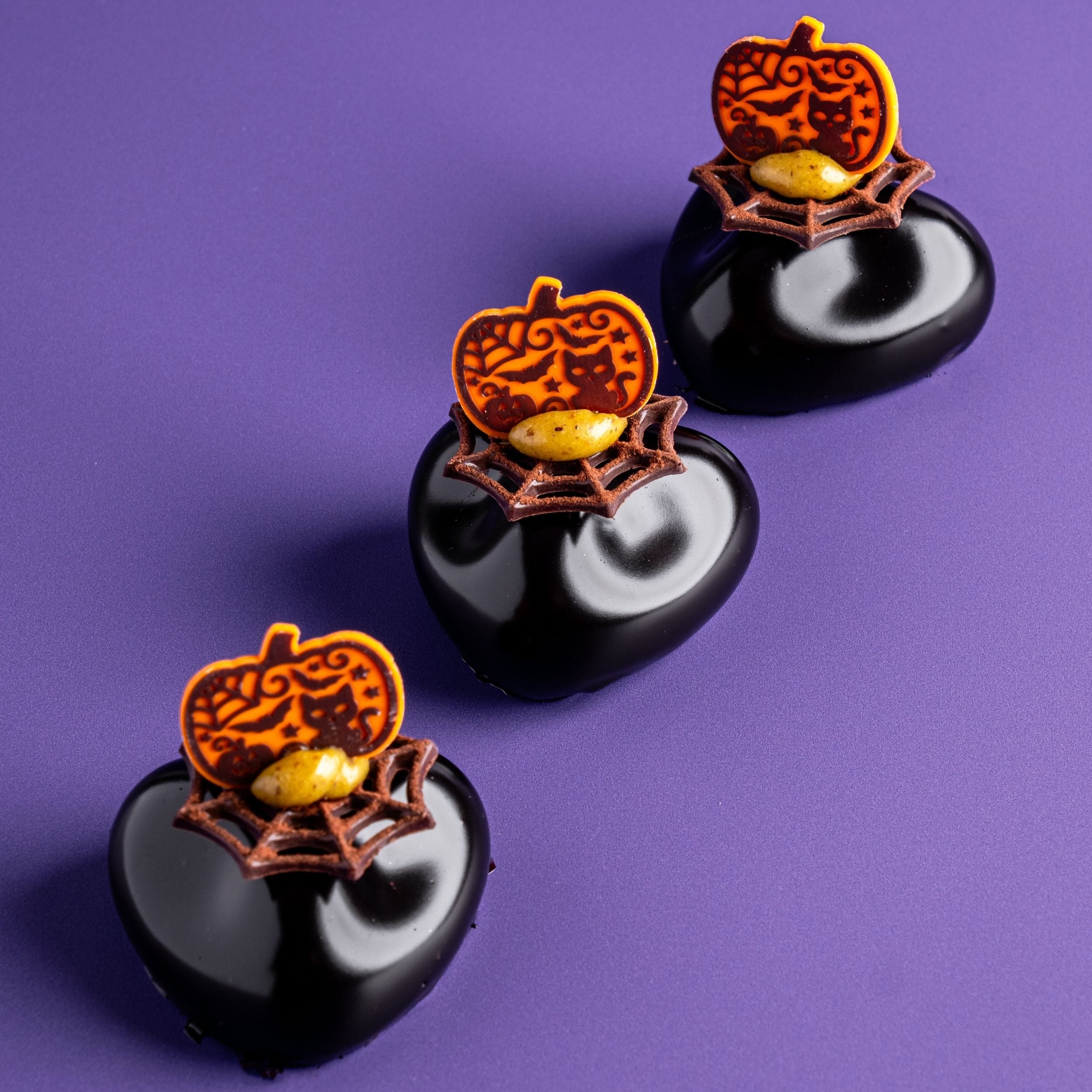 Tre mono in fila halloween con decorazioni in cioccolato ragnatela e zucca con gatto